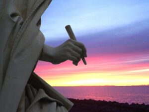 Scorcio di una statua, raffigurata con un carboncino in mano, pare che disegni i colori del tramonto, sullo sfondo