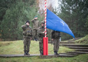 Cadetti sull'attenti dietro la bandiera NATO a mezz'asta