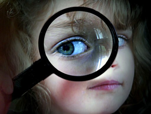 Una bambina usa una lente di ingrandimento