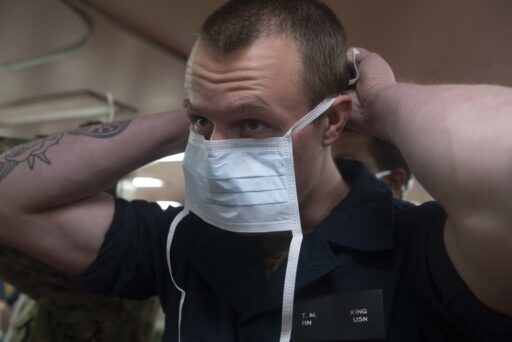 Un uomo intento a indossare una mascherina chirurgica