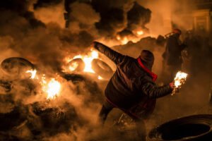 Un ragazzo lancia un molotov tra le fiamme