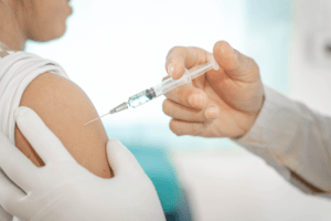 Un medico, intento ad iniettare un vaccino nel braccio di un paziente