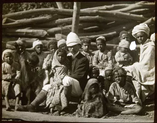 foto scattata nell'India dell'epoca coloniale: un colono siede in mezzo ai locali