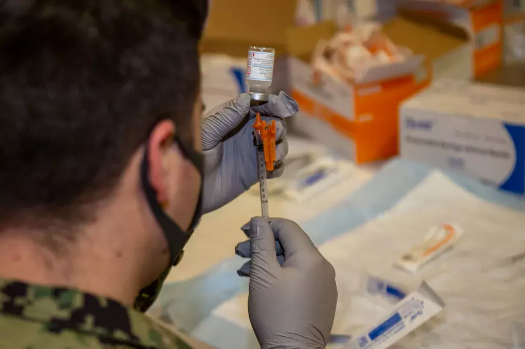 un militare analizza il contenuto di una fiala di vaccino